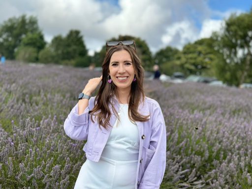 Emma stood in a lavender field with a lilac jacket and lilac earrings