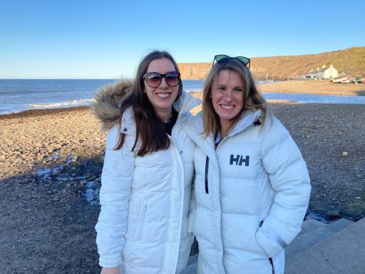 Emma and Karen in matching white coats in Saltburn in the winter sunshine